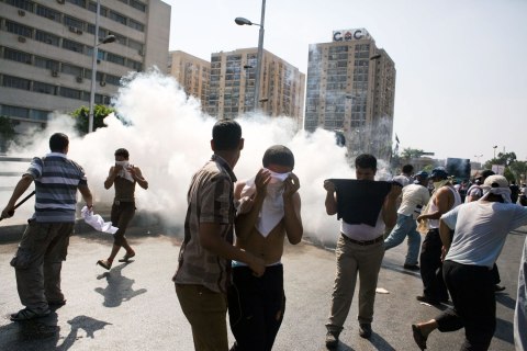 Egyptian protesters take cover from tear gas during clashes next to the headquarters of the Republican Guard, in Cairo, on July 5, 2013.