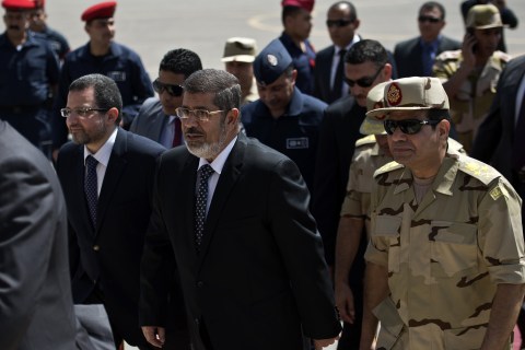 From left: Egyptian Prime Minister Hisham Qandil, President Mohamed Morsi, and Defense Minister Abdelfatah al-Sissi arrive at Almaza military Airbase in Cairo on May 22, 2013 to attend the welcoming of the policemen and soldiers who were seized in Sinai by kidnappers following their release.
