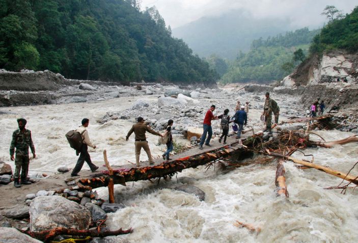 Indian army personnel help stranded people cross a flooded river after heavy rains in the Himalayan state of Uttarakhand