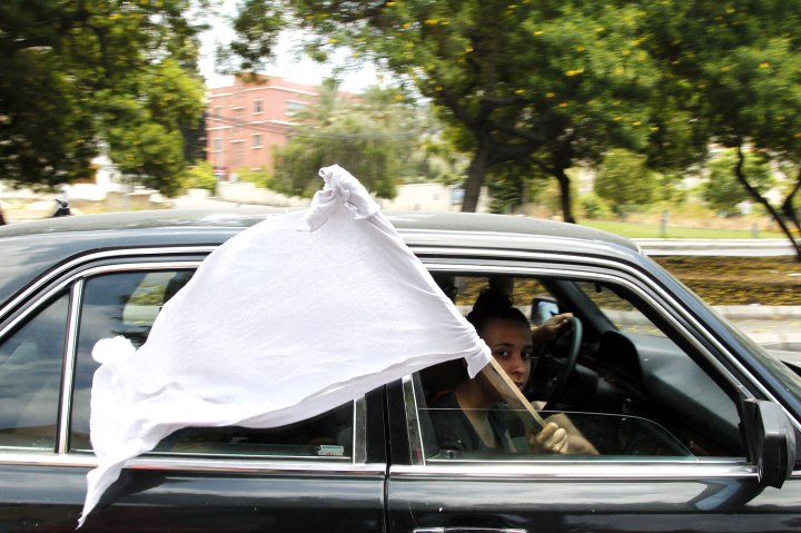 A girl holds a white flag to show that civilians are in the car, during clashes in Abra near Sidon