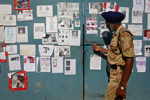 A security personal opens a gate covered in posters of missing people, affected by the flash floods and landslides, at the Indian Air Force base in Dehradun
