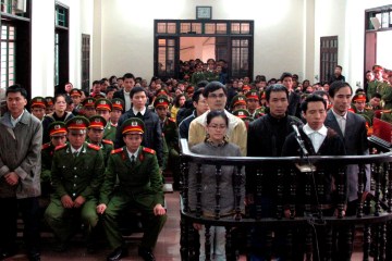 Defendants stand in front of dock at a court in Nghe An province, south of Hanoi
