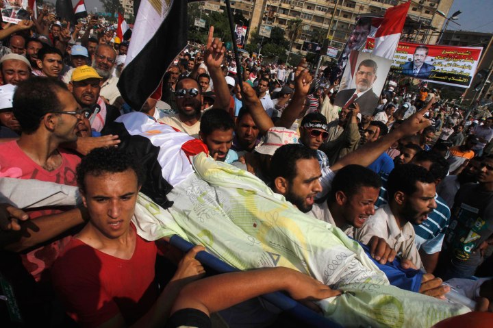 Supporters of Egypt's deposed President Mohamed Morsi carry the body of a fellow supporter killed by violence outside the Republican Guard headquarters in Cairo, on July 8, 2013.