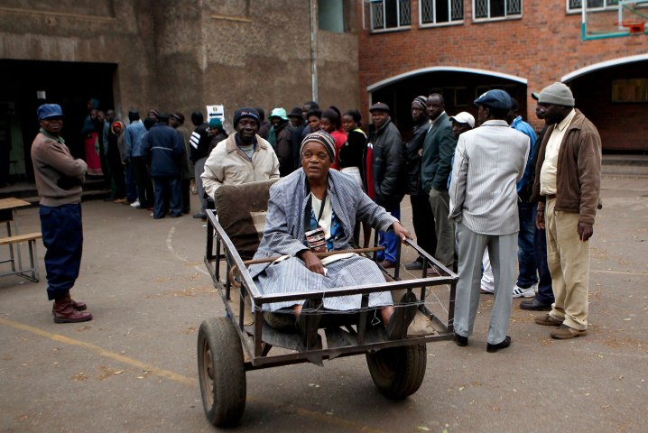 Majika is transported on a push cart after casting her vote in Mbare township