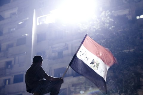 A boy sits on a traffic signal holding the Egyptian national flag during a demonstration against President Morsi at Tahrir square in Cairo, on July 2, 2013.