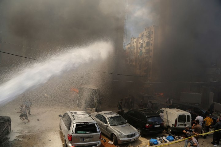 Civil Defence members extinguish fire at the site of an explosion in Beirut's southern suburbs