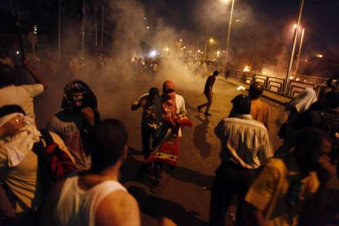People run for cover as security forces fire tear gas after shooting to disperse Islamist supporters of ousted president Mohamed Morsi outside the Republican Guard headquarters in Cairo, on July 8, 2013.