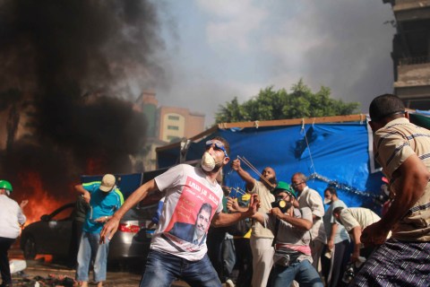 Supporters of the Muslim Brotherhood and Egypt's ousted president Mohamed Morsi throw stones during clashes with security forces in Cairo, on Aug. 14, 2013, as security forces backed by bulldozers moved in on two huge pro-Morsi protest camps.