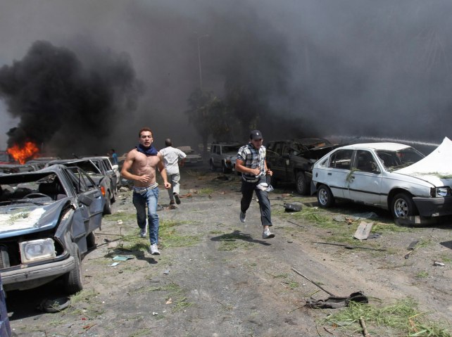 People run to help outside one of two mosques hit by explosions in Tripoli, Lebanon, on Aug. 23, 2013.