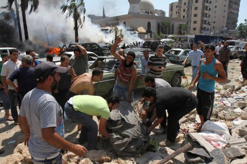 Men remove a dead body from the scene of an explosion outside one of two mosques in Lebanon's northern city of Tripoli, on Aug. 23, 2013.