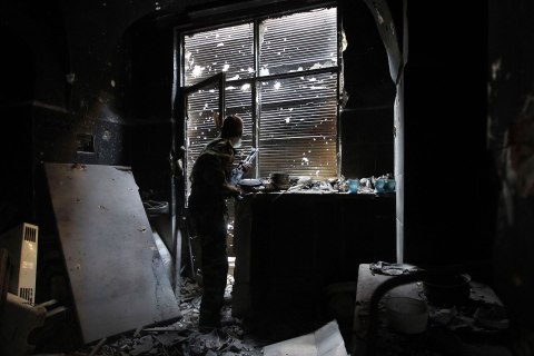 A Free Syrian Army fighter looks outside while holding his weapon as he takes cover inside a damaged shop in the old city of Aleppo