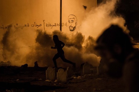 Protesters run from the toxic gas shot by riot police in Bahrain, on Aug. 5, 2013.