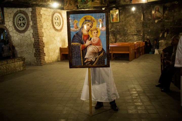 An Egyptian Coptic Christian man holds a picture of the Virgin Mary during preparations for a religious festival at Al-Mahraq monastery in Assiut, Upper Egypt, Aug. 6, 2013. 