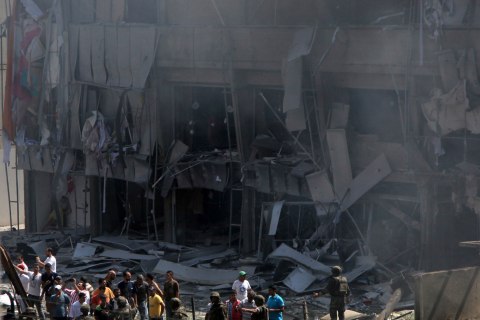 Lebanese citizens stand in front of a severely damaged building as they gather outside al-Salam mosque, near the house of former Lebanese police chief Ashraf Rifi, at the site of a powerful explosion in the Tripoli, Lebanon, on Aug. 23, 2013.