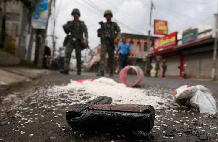 A weapon concealed in a bag of rice carried by a rebel lies on a road in downtown Zamboanga