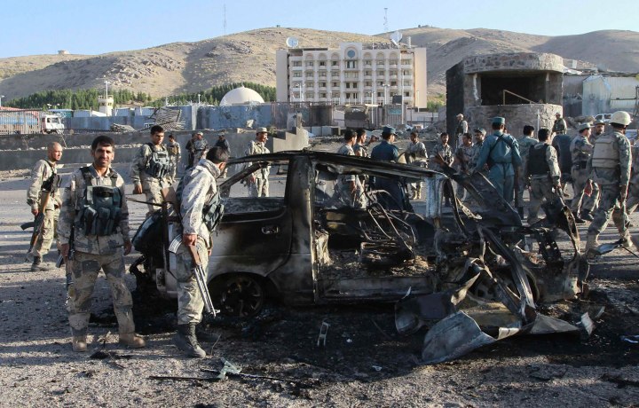 Afghan security forces inspect a damaged car, which was used during a suicide bomb attack, outside the U.S. consulate in Herat province