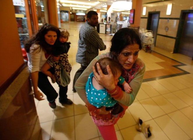 Women carrying children run for safety as armed police hunt gunmen who went on a shooting spree in Westgate shopping centre in Nairobi Sept. 21, 2013. 