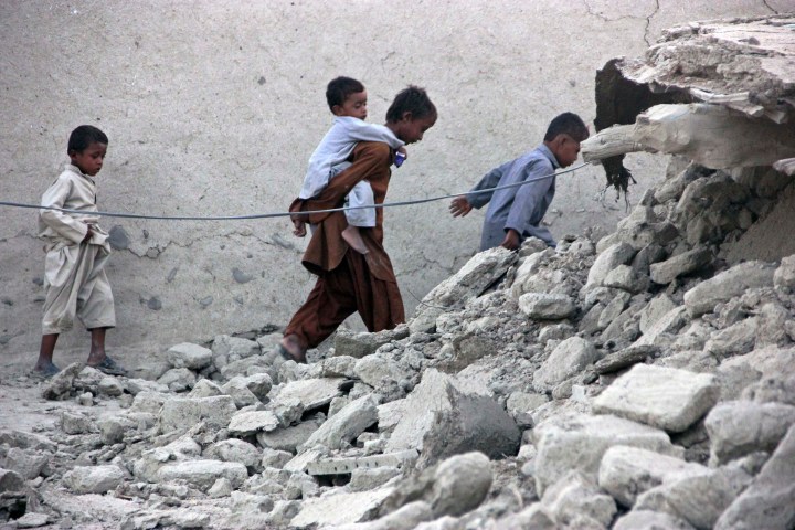 Survivors of an earthquake walk on rubble of a mud house after it collapsed following the quake in the town of Awaran, southwestern Pakistani province of Baluchistan, Sept. 25, 2013.