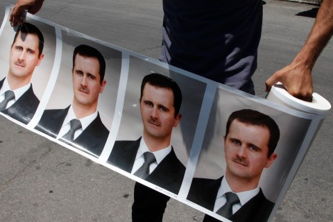 A man holds a roll of pictures of Syrian President Bashar al-Assad during a rally in Damascus