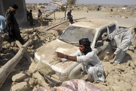 Pakistani survivors clear the debris of destroyed houses in the earthquake-devastated district of Awaran on September 25, 2013. 