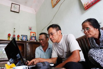 Le Dung, center, reads articles on the Internet with Dang Van Dat, left, and Tran Thi Thanh Kiem at his house in Van Giang district, outside Hanoi, on Aug. 19, 2012