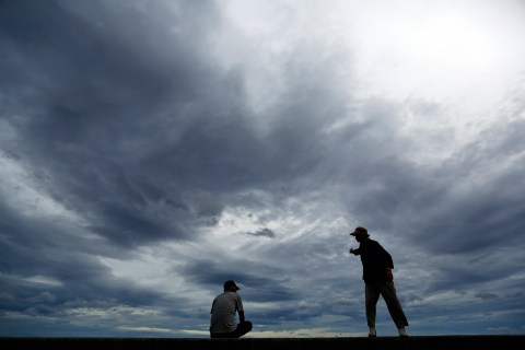 A man and a woman watch waves from atop anti-tsunami barriers after a storm in Iwaki, Fukushima Prefecture