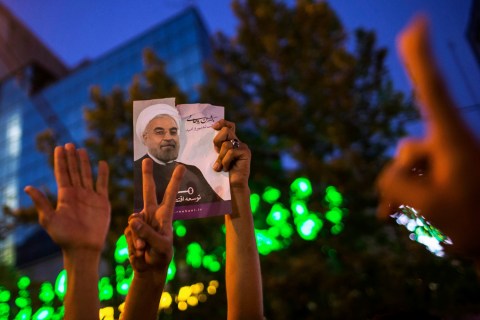 Supporters of moderate cleric Hassan Rohani hold a picture of him as they celebrate his victory in Iran's presidential election on a pedestrian bridge in Tehran