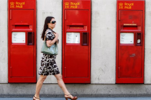 A woman passes a row of Royal Mail post boxes in London
