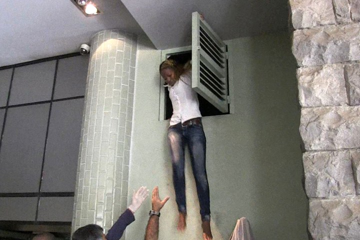 An image grab taken from AFP TV shows a Kenyan woman coming out of an air vent where she was hiding during an attack by masked gunmen at a shopping mall in Nairobi on September 21, 2013. 