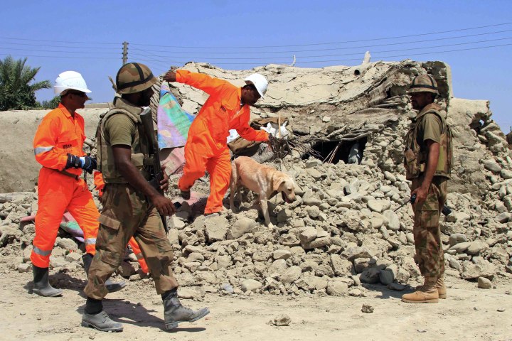 Pakistani Army soldiers patrol as rescue workers use sniffer dogs to search for the victims amid rubble of destroyed homes in earthquake-hit areas of Awaran, Balochistan province, Pakistan, Sept. 26 2013.