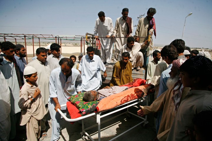 Survivors of an earthquake help to wheel a man who was injured in the quake, as he arrives from a remote village for treatment at a hospital in Awaran, southwestern Pakistani province of Baluchistan, Sept. 26, 2013.