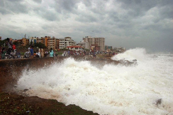 Indian people watch high tide waves as they stand at the Bay of Bengal coast in Vishakhapatnam, India, Oct. 12, 2013. 