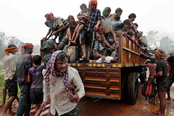 Evacuated Indian villagers get down from a truck at a relief camp as it rains near Berhampur, India, Oct. 12, 2013.