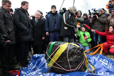 People look at what scientists believe to be a chunk of the Chelyabinsk meteor, recovered from Chebarkul Lake near Chelyabinsk, about 1500 kilometers (930 miles) east of Moscow, on Oct. 16, 2013.