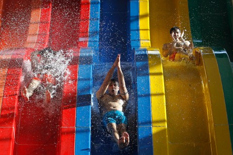 Youths slide down a huge water slide at a public swimming pool in Kabul