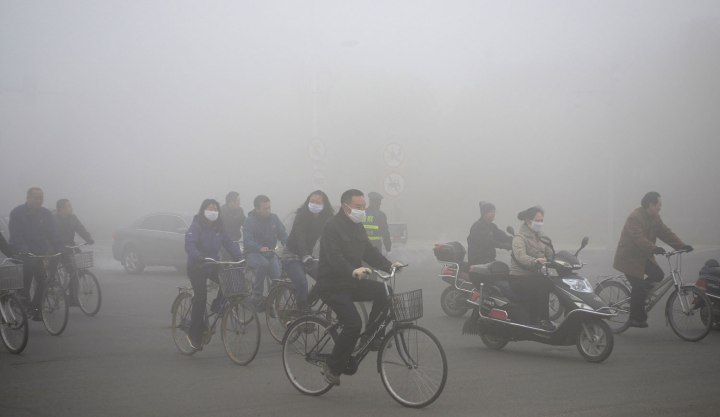 People ride along a street on a smoggy day in Daqing