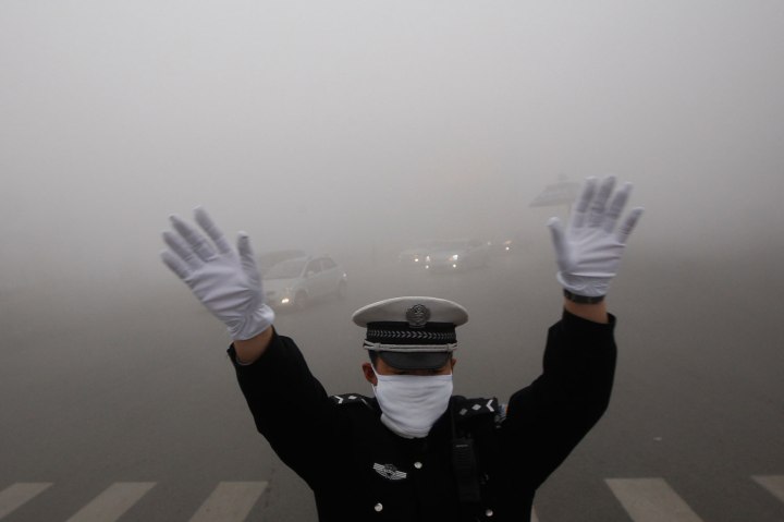 A traffic policeman signals to drivers during a smoggy day in Harbin
