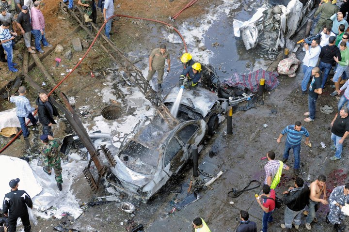 Lebanese firefighters hose down smouldering vehicles at the site of explosions close to the on Nov. 19, 2013.