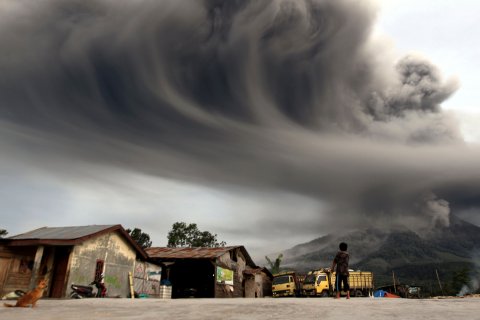 A woman in Sibintun village, Indonesia, watches as Mount Sinabung spews ash on Nov. 18, 2013.
