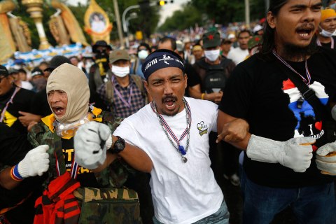 Anti-government protesters shout as they get ready to attack a police barricade near the Government house in Bangkok