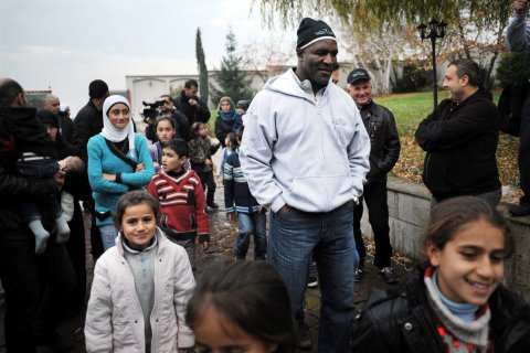 U.S. ambassador for Global Village NGO and former boxing champion Evander Holyfield walks with Syrian refugee families into a hotel in Sofia on November 11, 2013.
