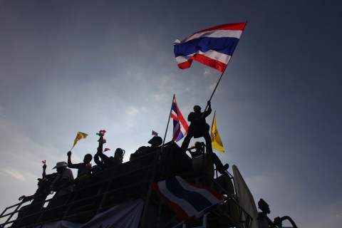 A protester waves a Thai national flag atop a truck at the Democracy Monument in central Bangkok