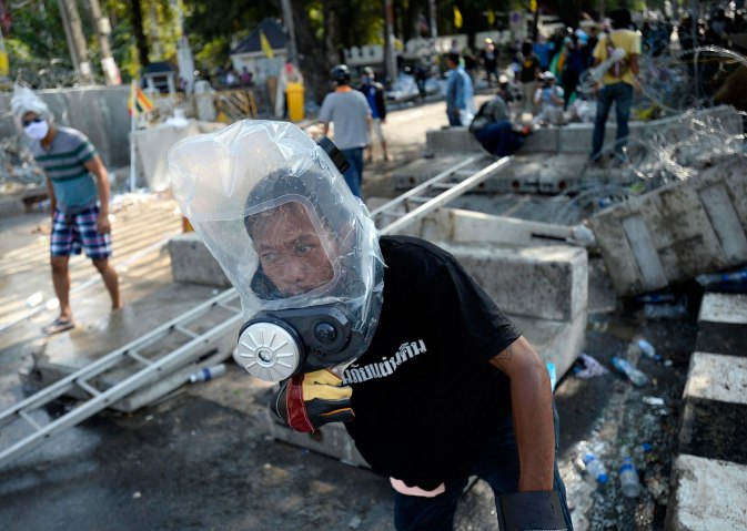 An anti-government protester uses personalised protective gear as they attempt to remove barricades outside Government House in Bangkok