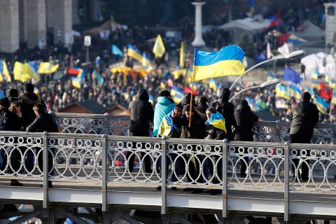 A man carrying an Ukranian flag gestures as he stands on top of a bridge overlooking Independence Square in Kiev