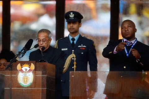 India's President Mukherjee speaks at the podium as a sign language interpreter punches air beside him during a memorial service for late South African President Nelson Mandela in Johannesburg