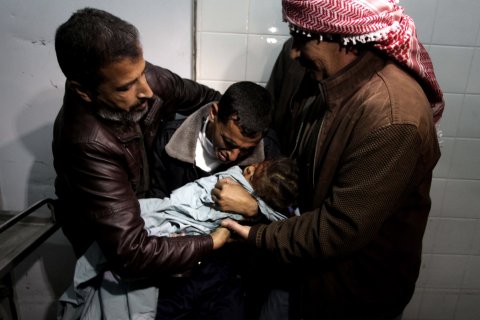 A Palestinian relative carries the lifeless body of Hala Abu Sebakha, who medics said was killed by shrapnel during an Israeli air strike on the Al Maghazi camp, at the morgue of Al-Aqsa hospital in Deir Al Balah, central Gaza Strip, on Dec. 24, 2013.