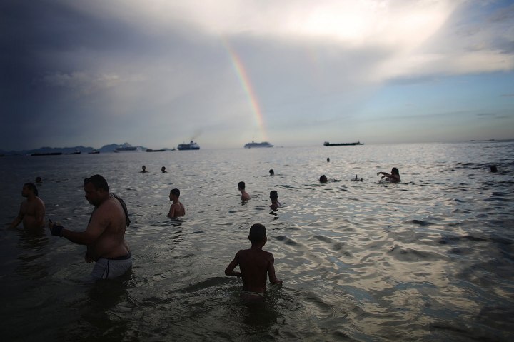 People swim at Copacabana Beach in front of a rainbow during New Year's Eve celebrations on Dec. 31, 2013 in Rio de Janeiro.