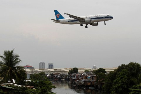 A China Southern Airlines aircraft flies over a slum before landing at Manila's International airport