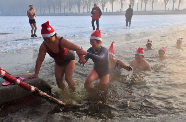 Winter swimmers wearing Santa Claus hats get out of a partially frozen lake after swimming in icy water to celebrate Christmas at a park in Shenyang, Liaoning province, China, on Dec. 24, 2013. 