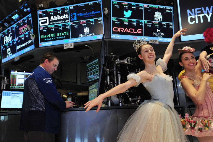 A trader works as New York City Ballet dancers pose on the floor of the New York Stock Exchange after ringing the opening bell Dec. 24, 2013 in New York City.